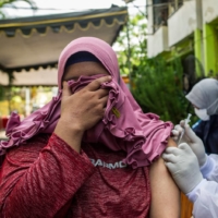 A health worker inoculates a resident with a Sinovac COVID-19 vaccine at a housing complex in Surabaya, Indonesia, on Sunday.  | AFP-JIJI