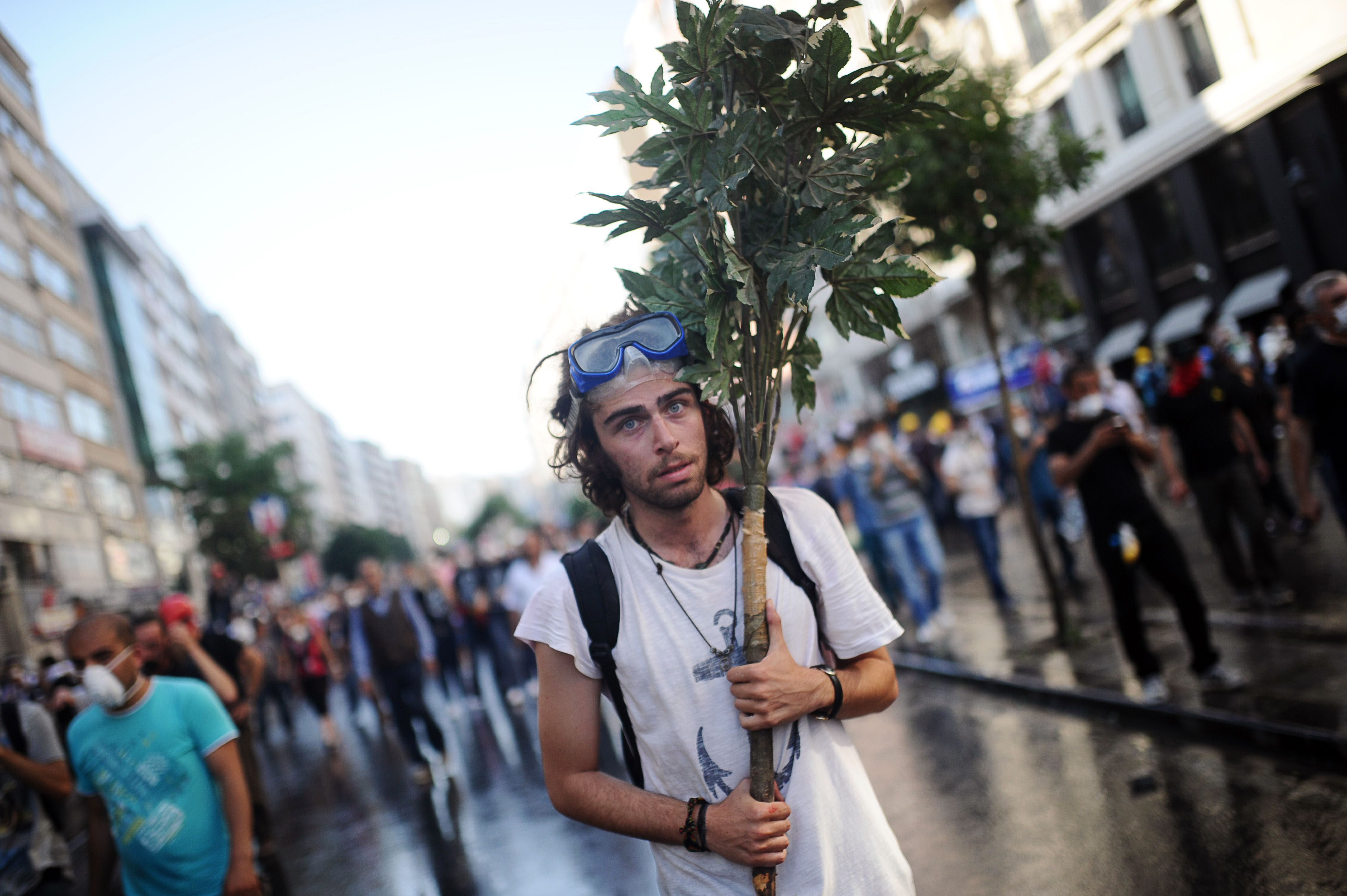 Going out on a limb: A protester holds tree branches during clashes between riot police and demonstrators in the streets adjacent to Taksim Square in Istanbul on Sunday. | AFP-JIJI