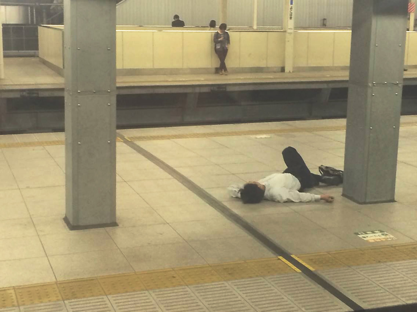 Too drunk to care: A nomi-sugi reveler rests on the platform at Yokohama Station. | BEN STUBBINGS