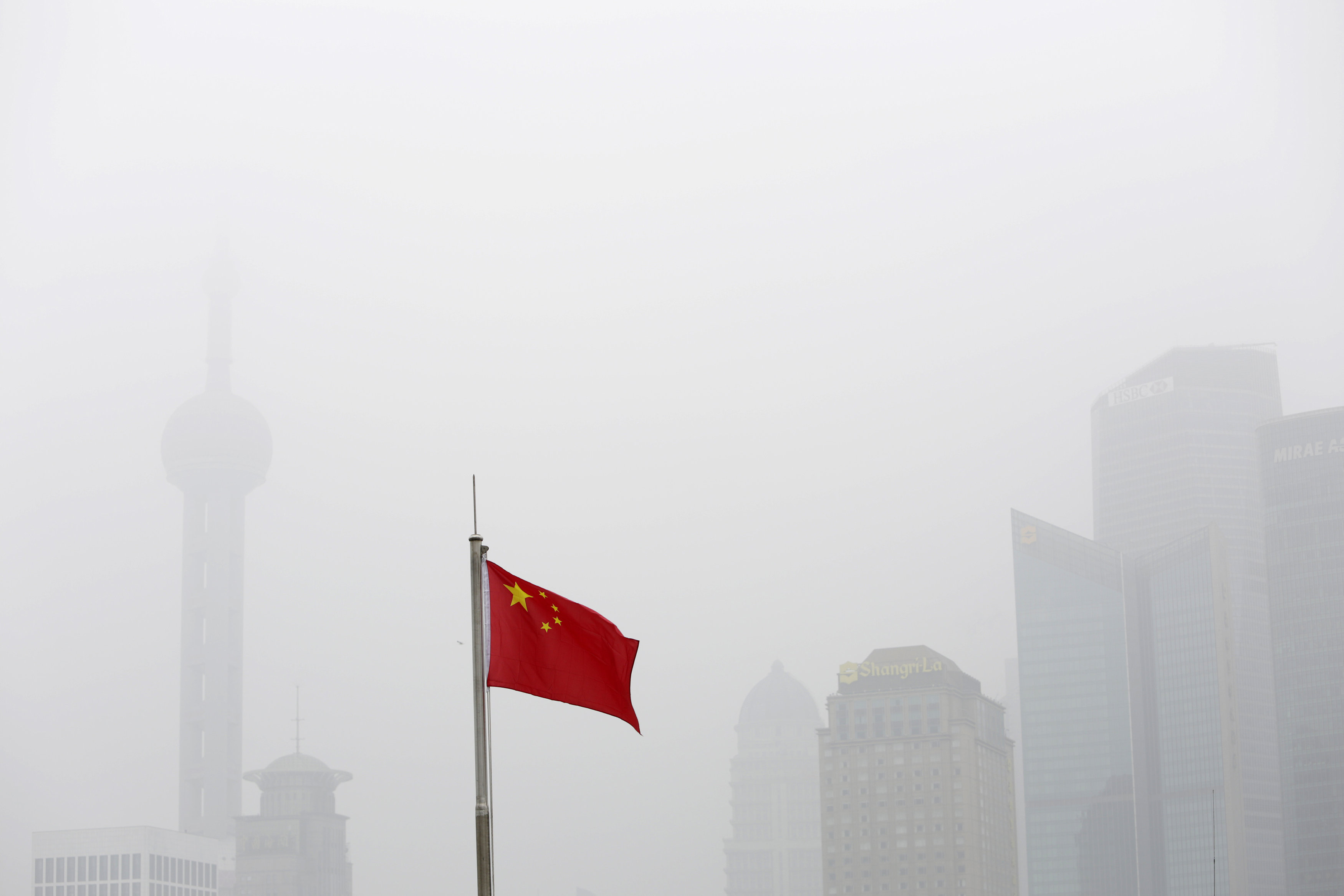 In the air: A Chinese flag is seen in front of the financial district of Pudong amid heavy smog in Shanghai. | REUTERS
