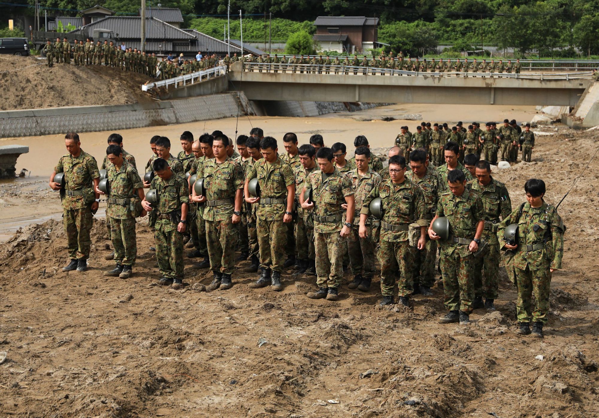Self-Defense Forces solders hold a minute's silence for victims prior to beginning search operations in a flooded area of Asakura, Fukuoka Prefecture, on Wednesday, two weeks after heavy rains and flooding in Kyushu. Prime Minister Shinzo Abe's hope of enshrining the constitutionality of the SDF in the nation's top law is looking increasingly difficult to achieve as his support drops. | AFP-JIJI