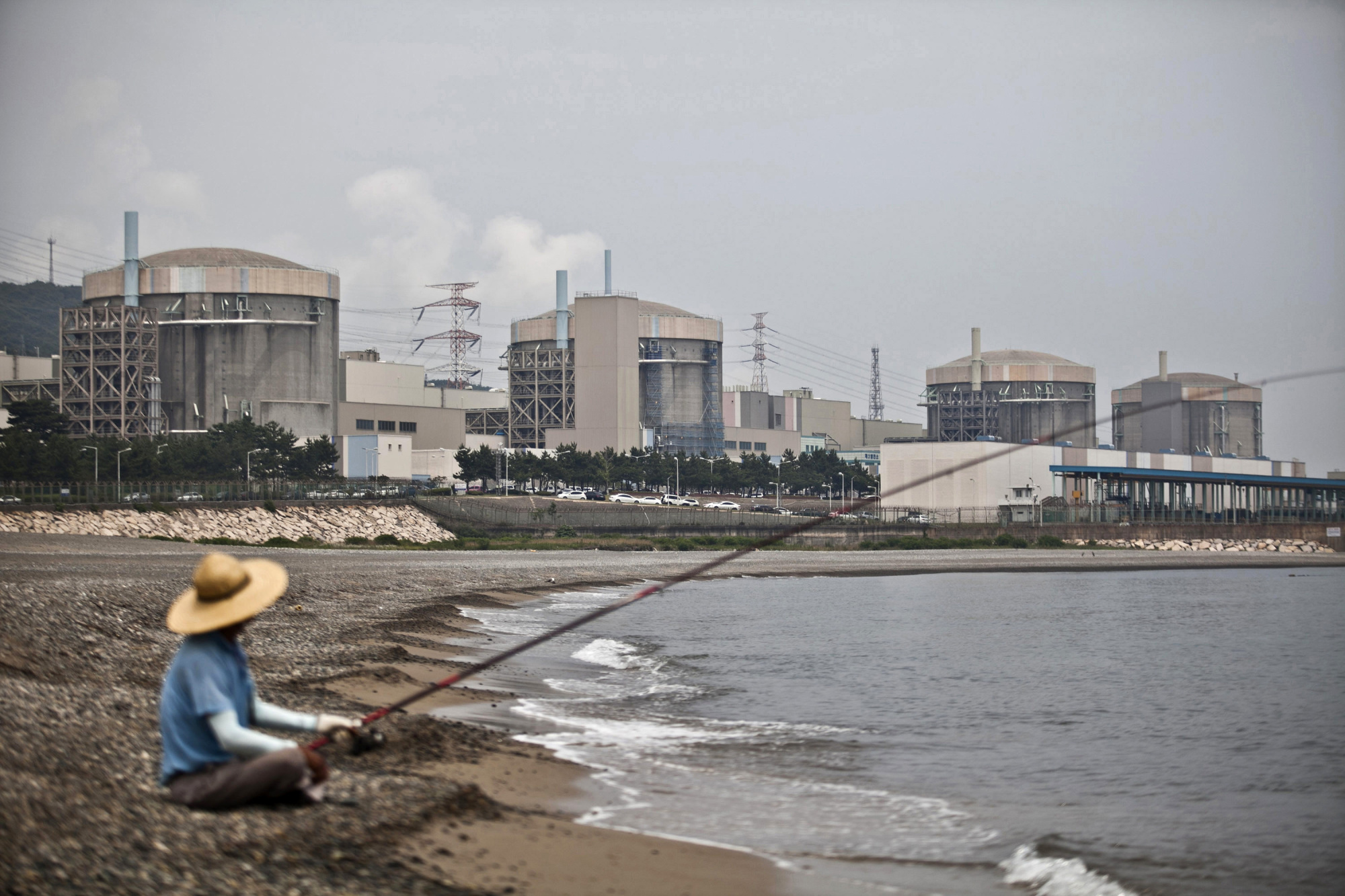 A man fishes in front of the Wolsong Nuclear Power Plant in Gyeongju, South Korea. Last month, President Moon Jae-in promised to scrap plans for new nuclear plants, not extend the life of existing ones, shut down 10 old coal power plants and cancel new coal projects. | BLOOMBERG